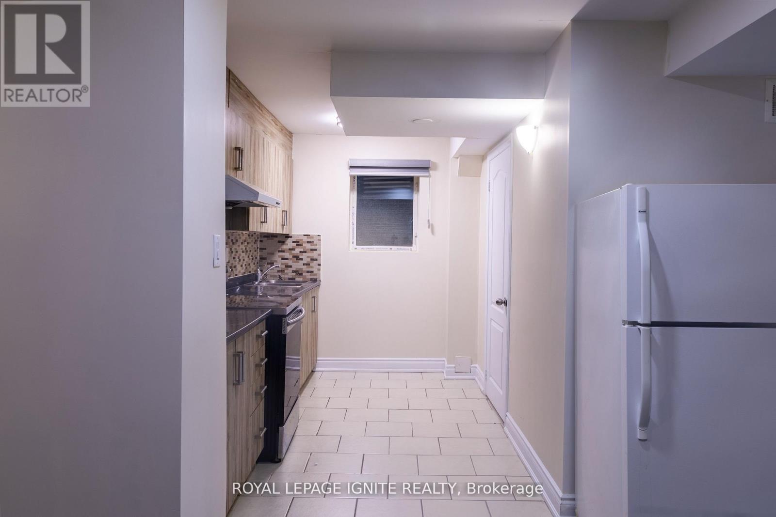 A kitchen with a refrigerator on the right and a window in the middle of the room.