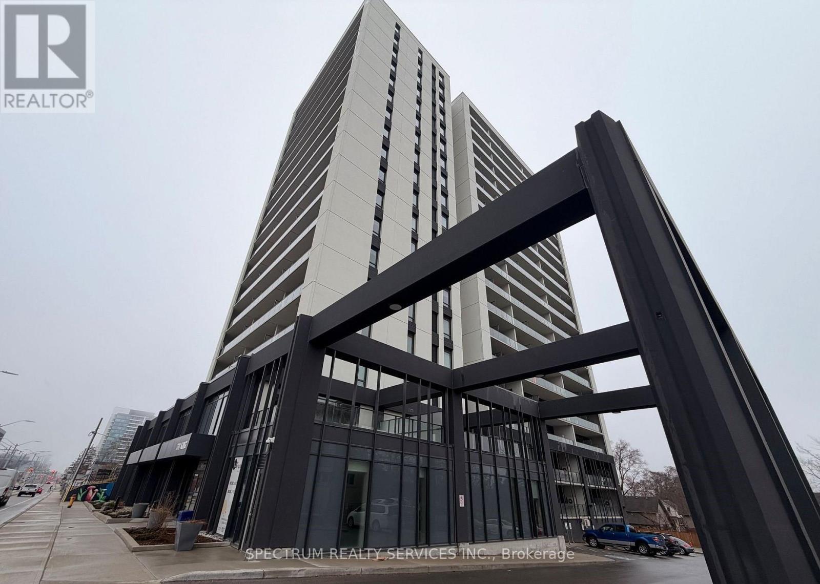 A tall building with a glass facade and a large metal structure in the foreground.