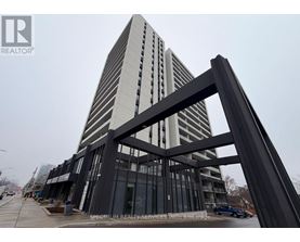 A tall building with a glass facade and a large metal structure in the foreground.