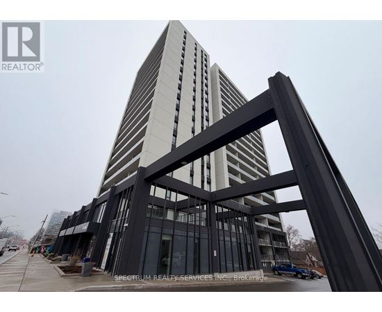 A tall building with a glass facade and a large metal structure in the foreground.