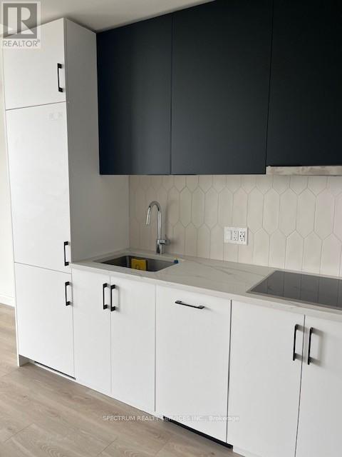 A kitchen with white cabinets and a black backsplash.