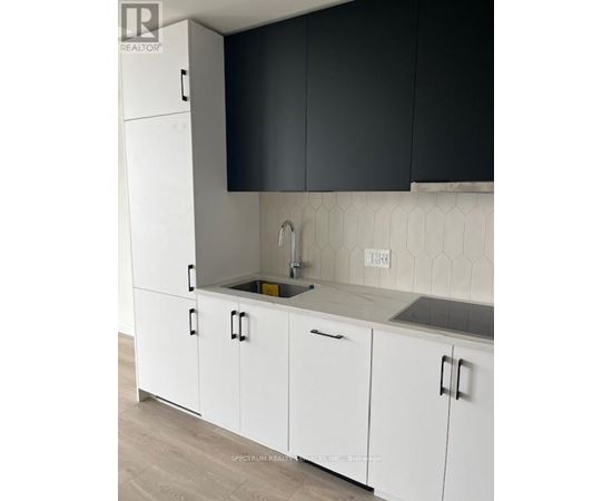 A kitchen with white cabinets and a black backsplash.