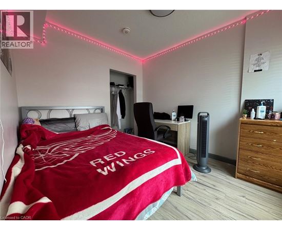 A bedroom with a bed covered in a Red Wings blanket.