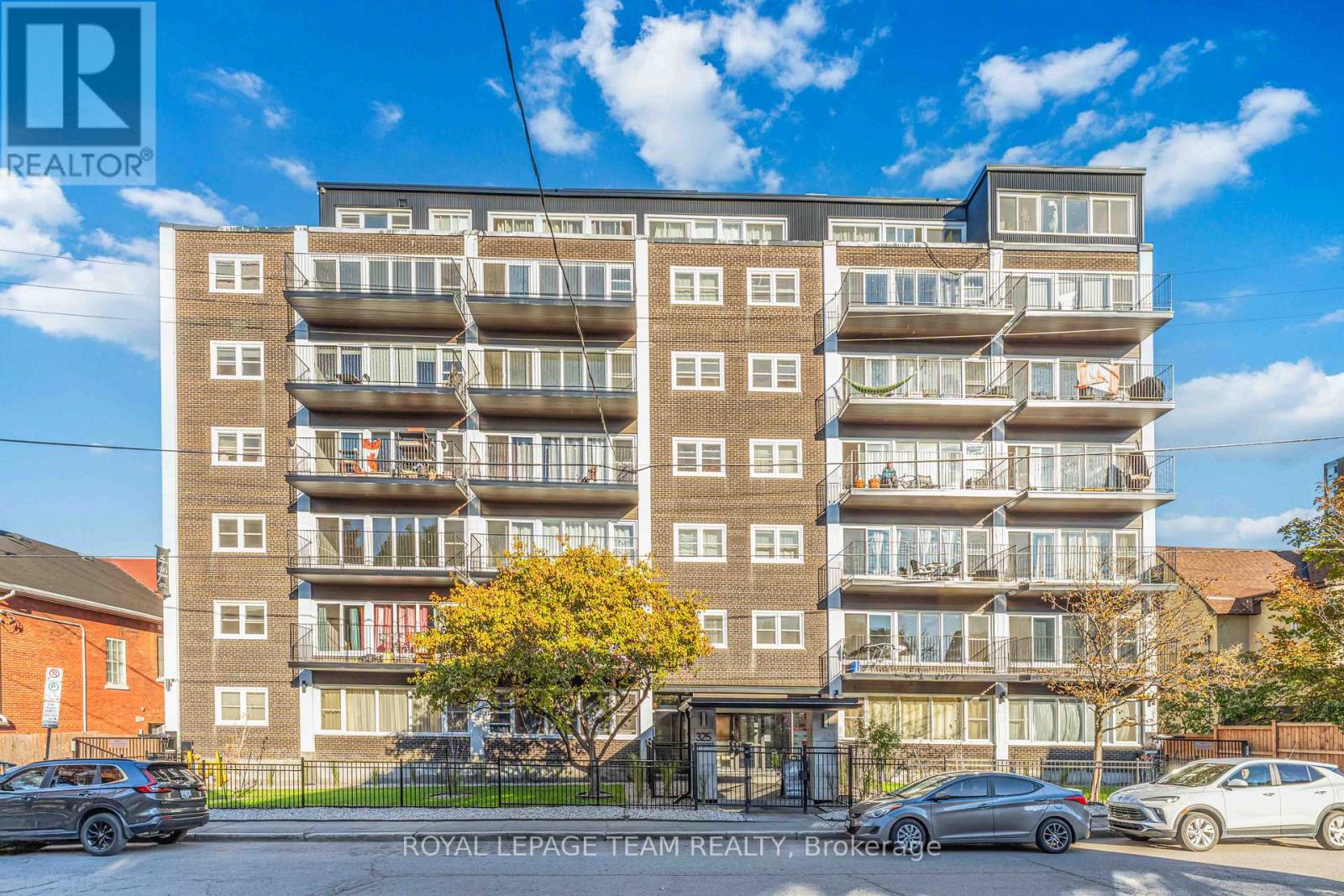 A multi-story apartment building with cars parked in front.