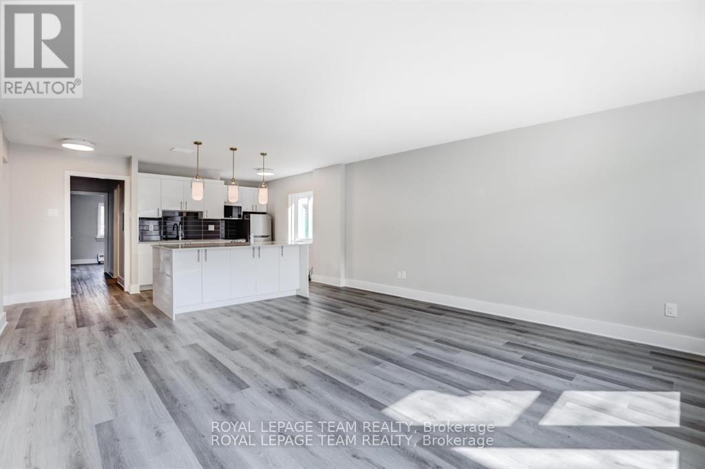 A spacious room with wooden flooring and white walls.