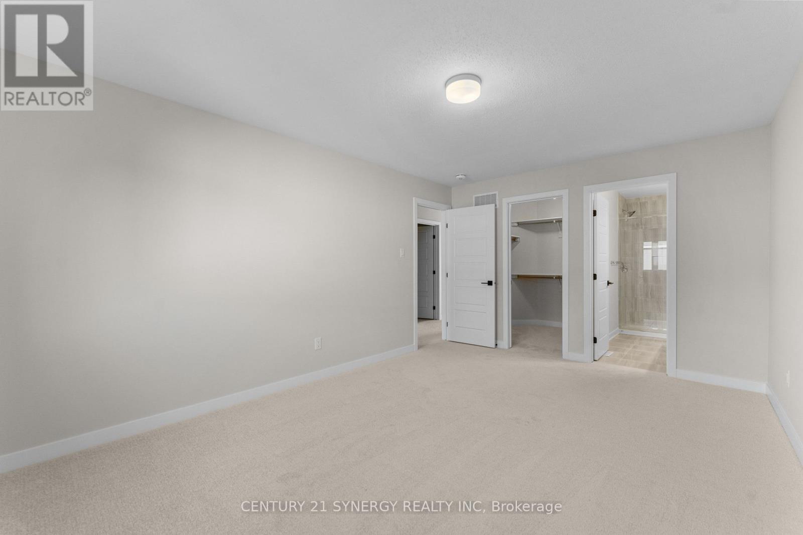 A white bedroom with a carpet floor and a ceiling light.