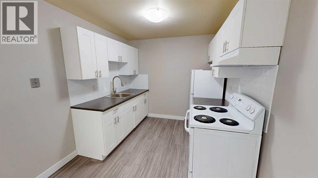A small kitchen with white cabinets and a stove top oven.