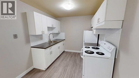 A small kitchen with white cabinets and a stove top oven.
