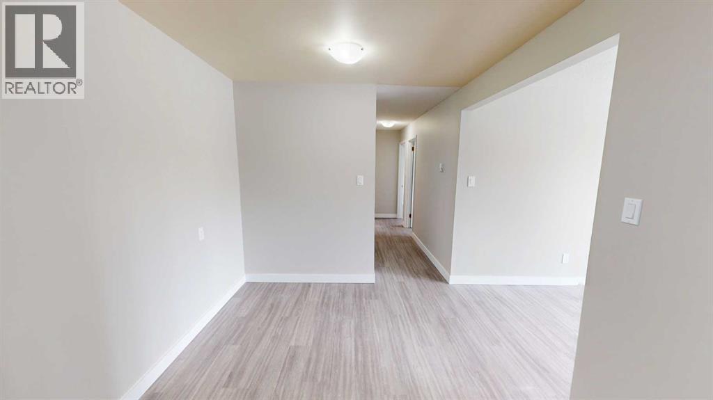 A spacious room with a wooden floor and white walls.