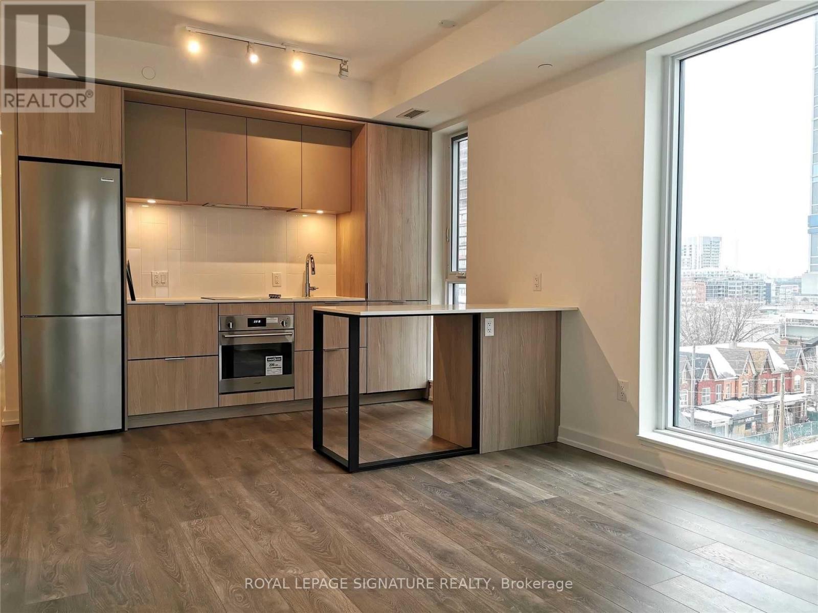 A kitchen with wooden cabinets and a stainless steel refrigerator.