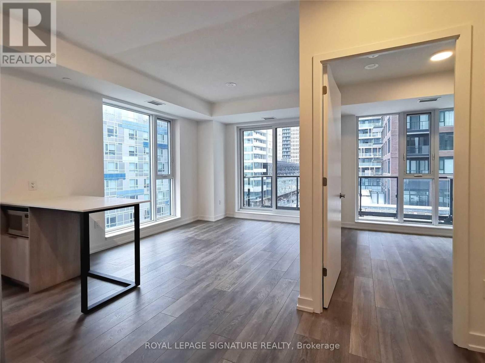 A spacious room with wooden floors and a large window overlooking a cityscape.