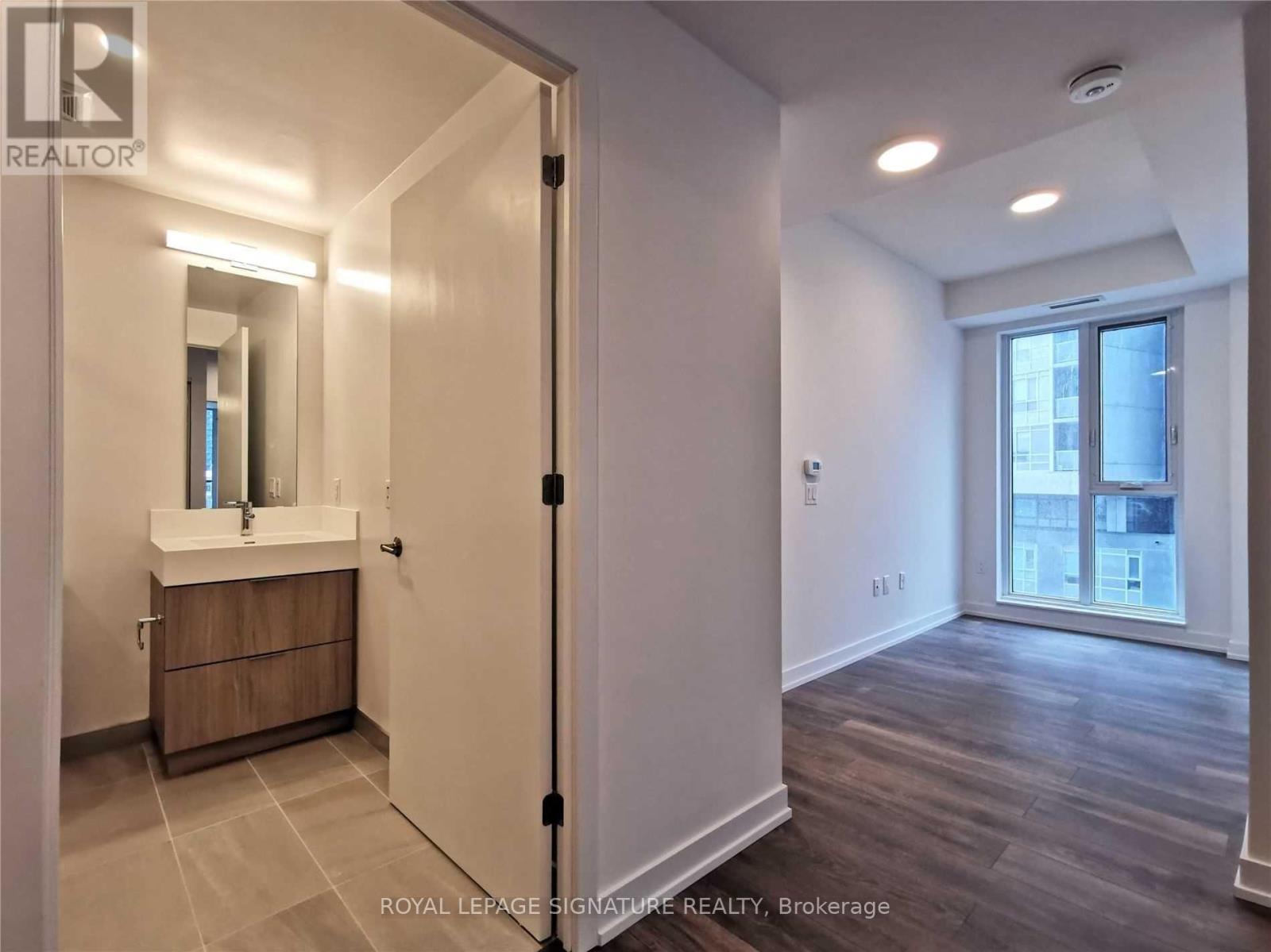 A bathroom with a sink, mirror, and wooden floors.
