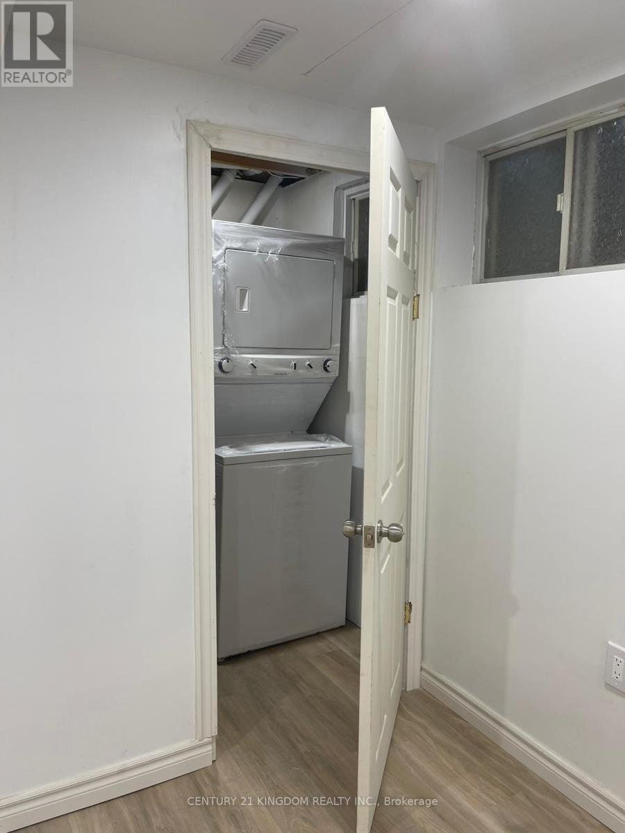 A white door is open to a small kitchen with a refrigerator and a cabinet.