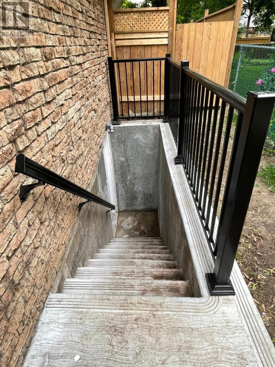 A set of stairs with a black railing and a brick wall on one side.