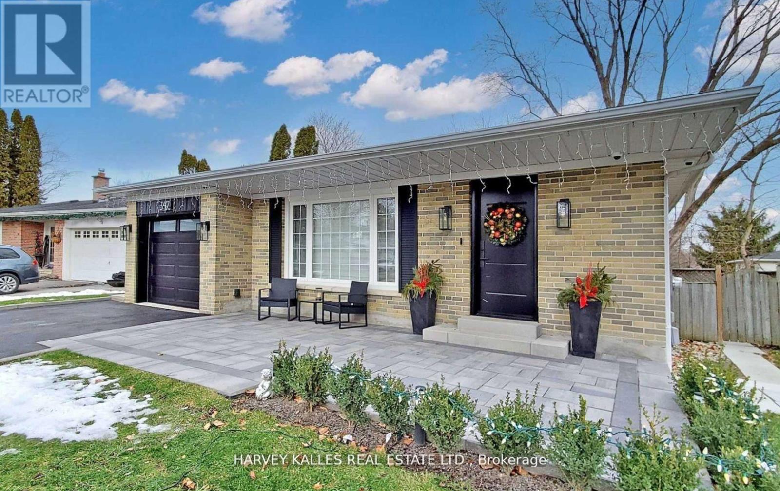 A real estate listing photo of a brick house with a black door and a wreath on the door.