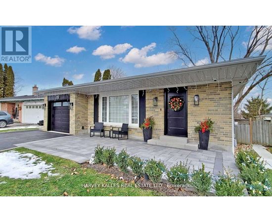 A real estate listing photo of a brick house with a black door and a wreath on the door.