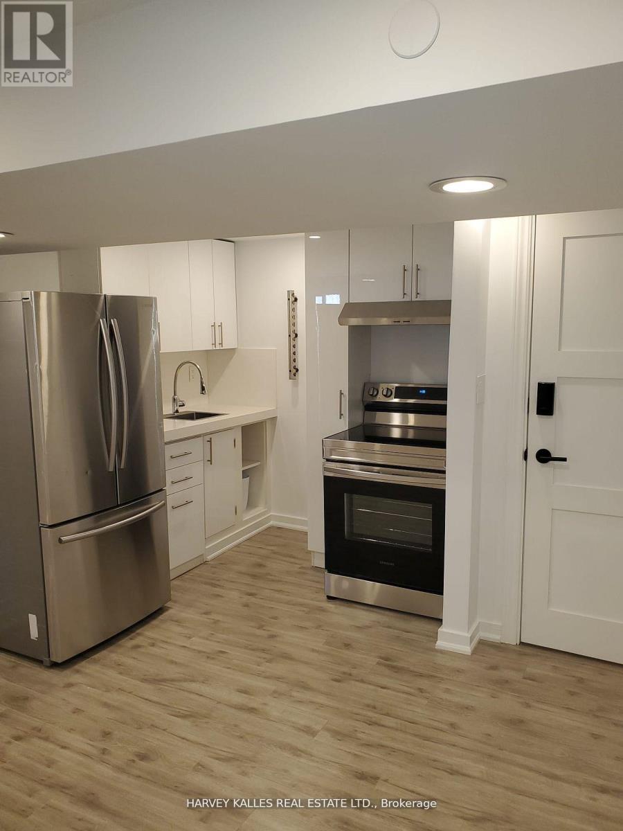 A modern kitchen with a stainless steel refrigerator and wooden flooring.