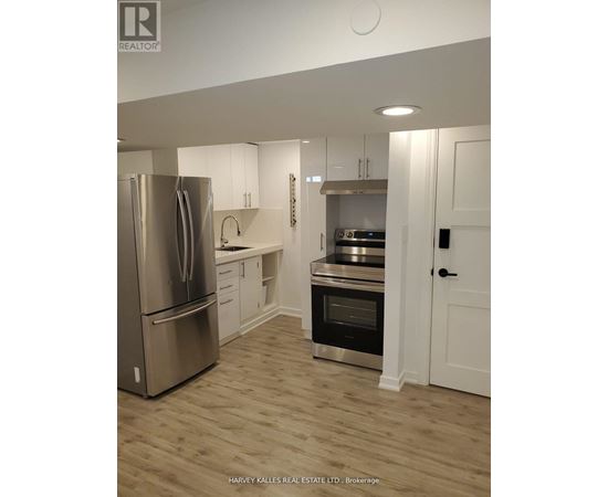 A modern kitchen with a stainless steel refrigerator and wooden flooring.