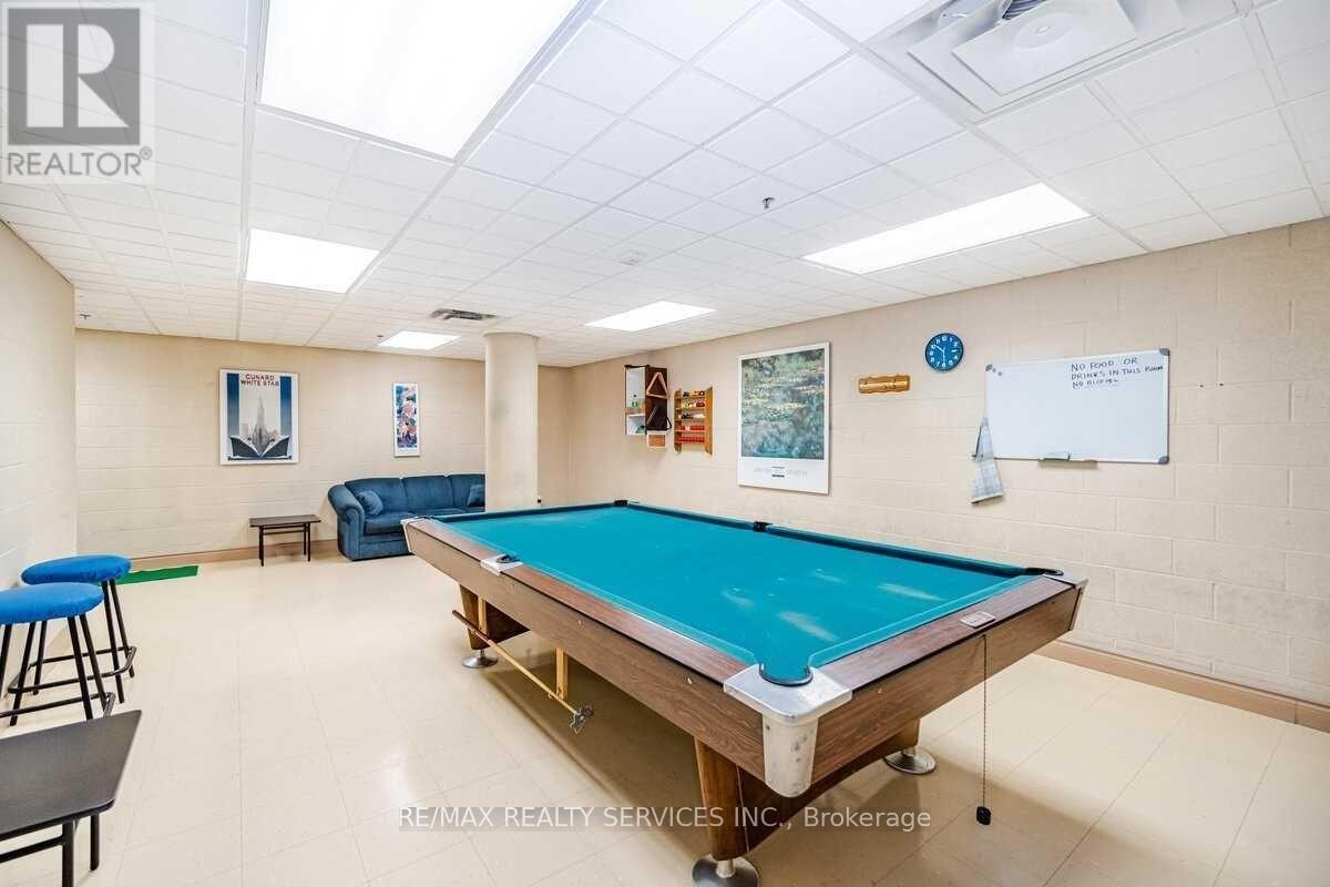 A pool table is in the middle of a room with a whiteboard and a blue chair.