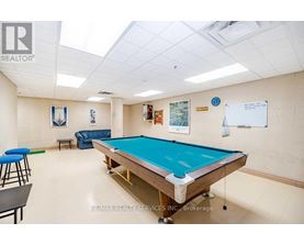 A pool table is in the middle of a room with a whiteboard and a blue chair.