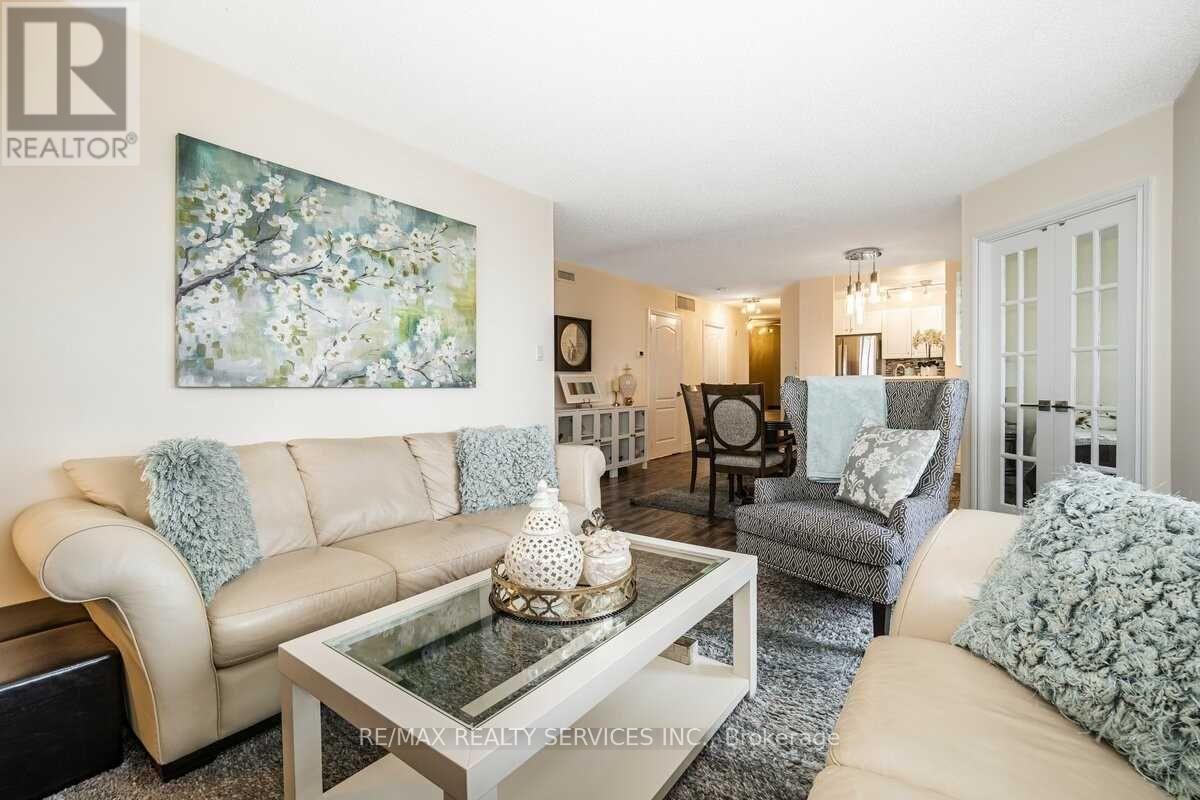 A living room with a beige couch, a glass coffee table, and a painting on the wall.