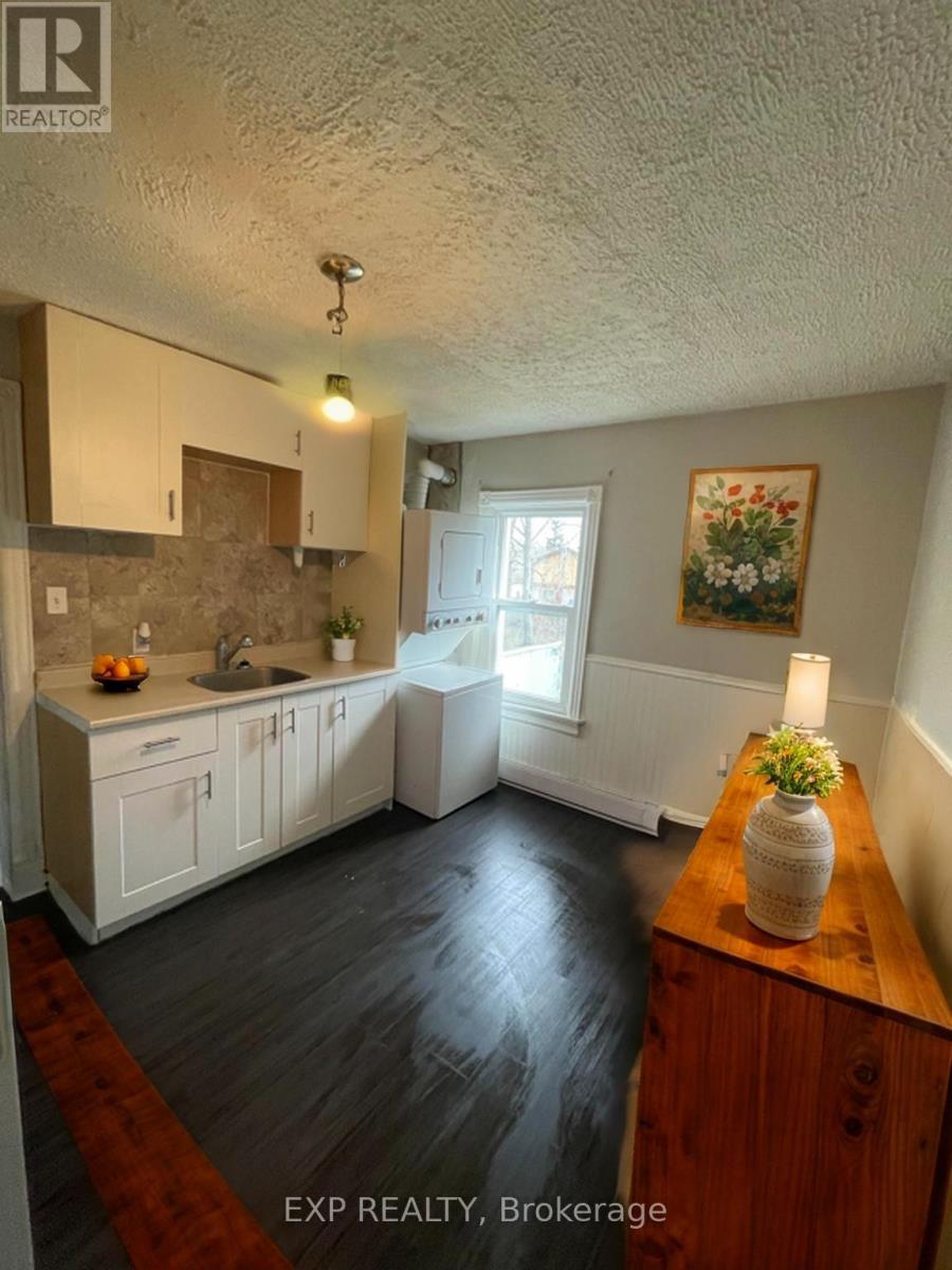 A kitchen with white cabinets and a wooden table with a vase on it.