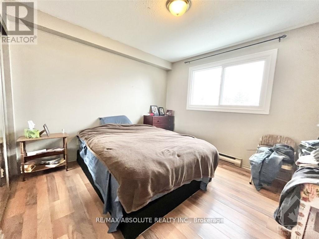 A bedroom with a bed, nightstand, and window.