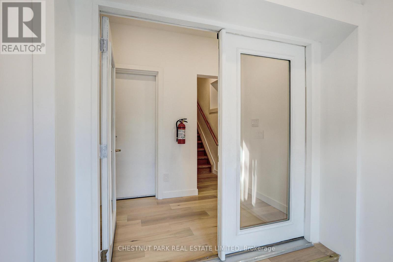 A white door with a glass window is open to a hallway.