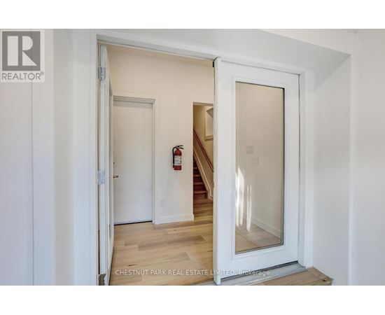 A white door with a glass window is open to a hallway.