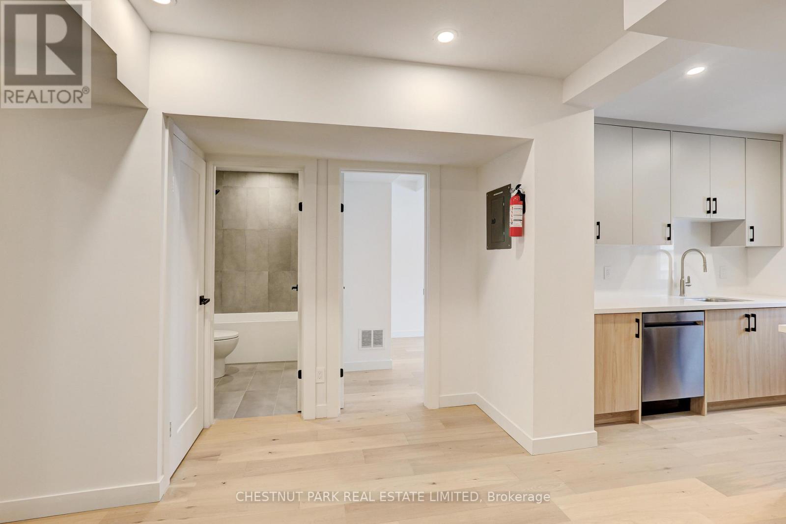 A modern kitchen with white cabinets and a wooden floor.