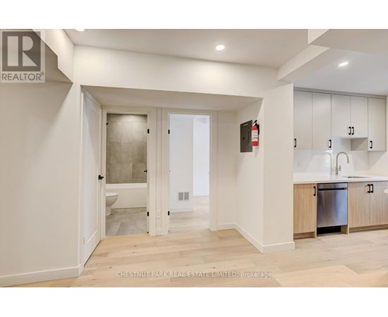 A modern kitchen with white cabinets and a wooden floor.
