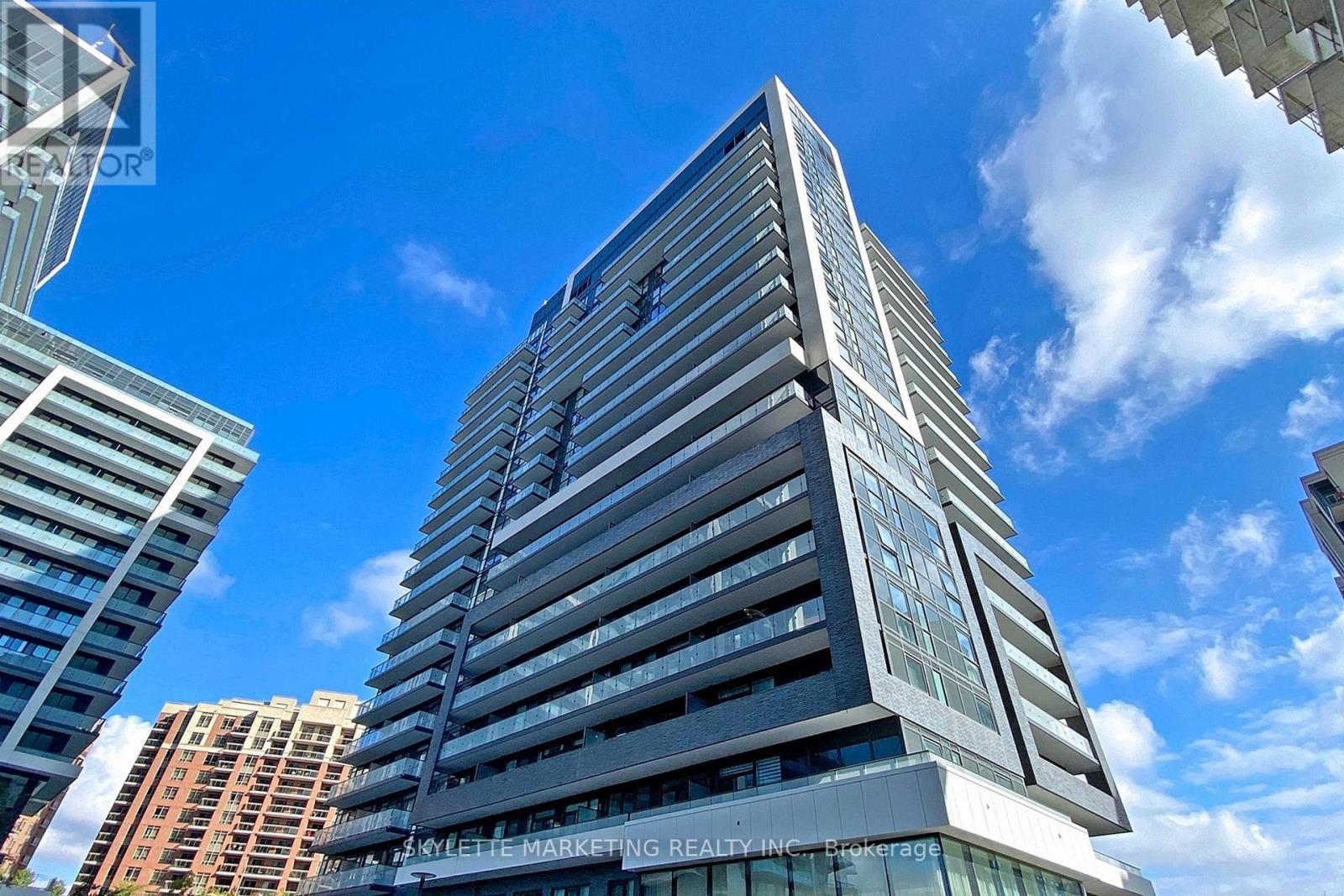 A tall building with a sign that reads "The Marketing Realty Inc." is seen against a blue sky.
