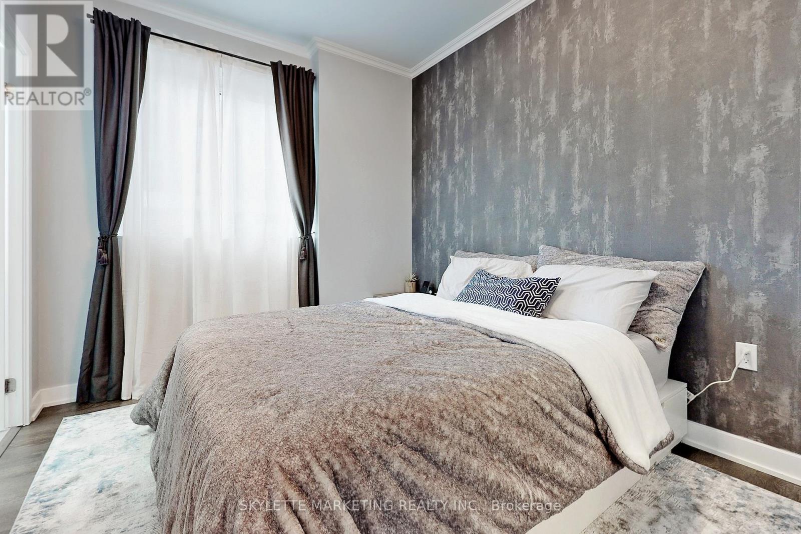 A bedroom with a large bed and a window with curtains.