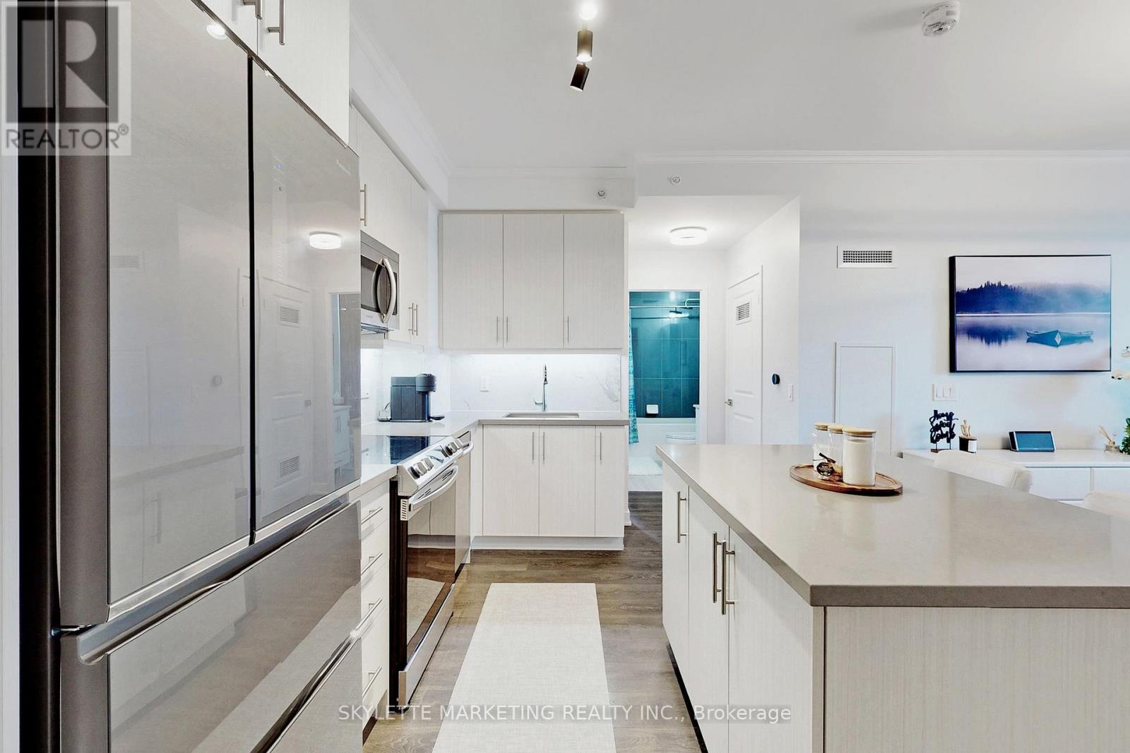 A modern kitchen with white cabinets and a stainless steel refrigerator.