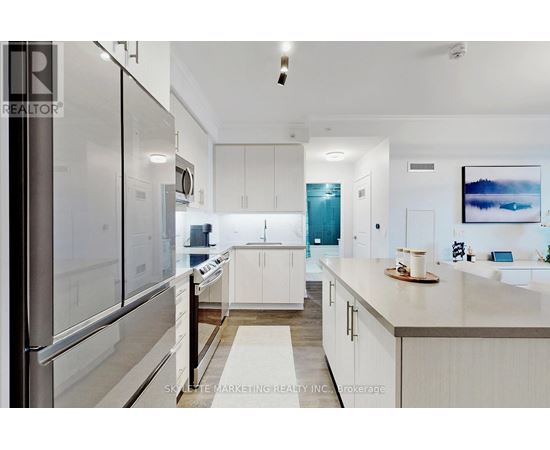 A modern kitchen with white cabinets and a stainless steel refrigerator.