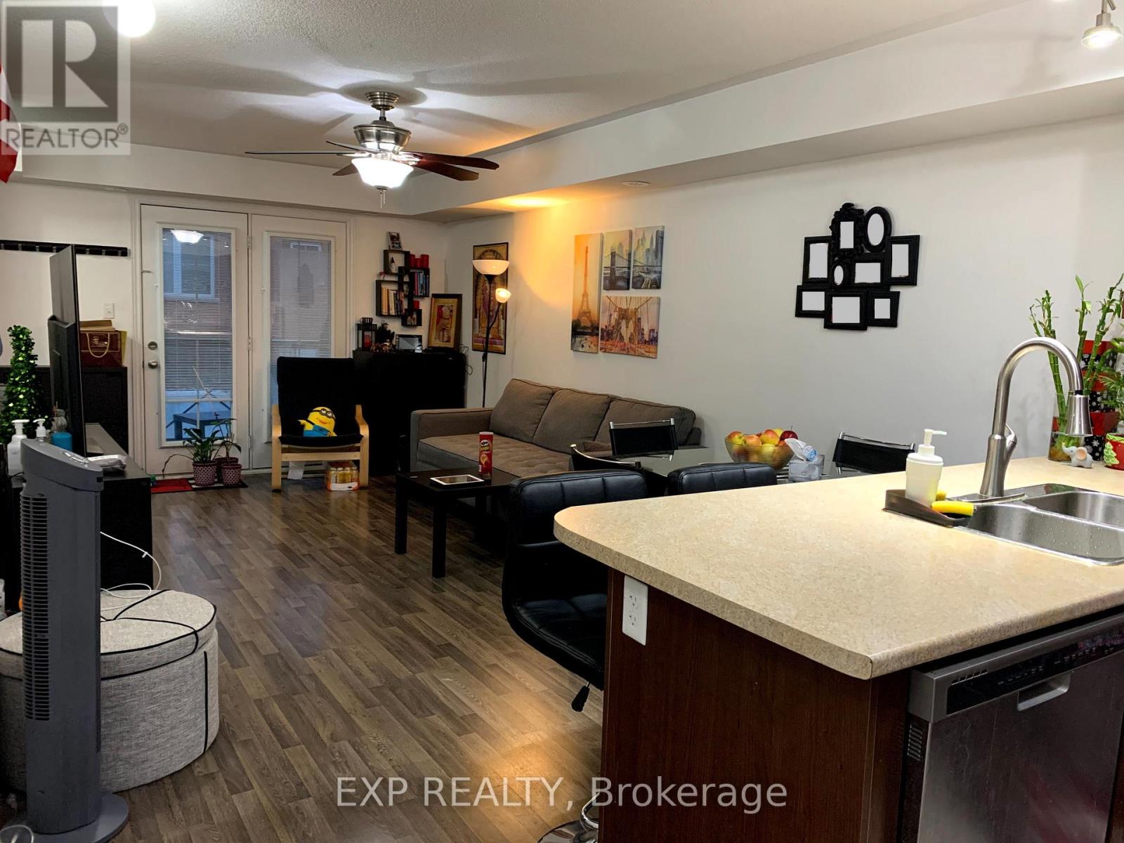 A living room with a couch, a television, and a kitchen area with a sink and a counter.