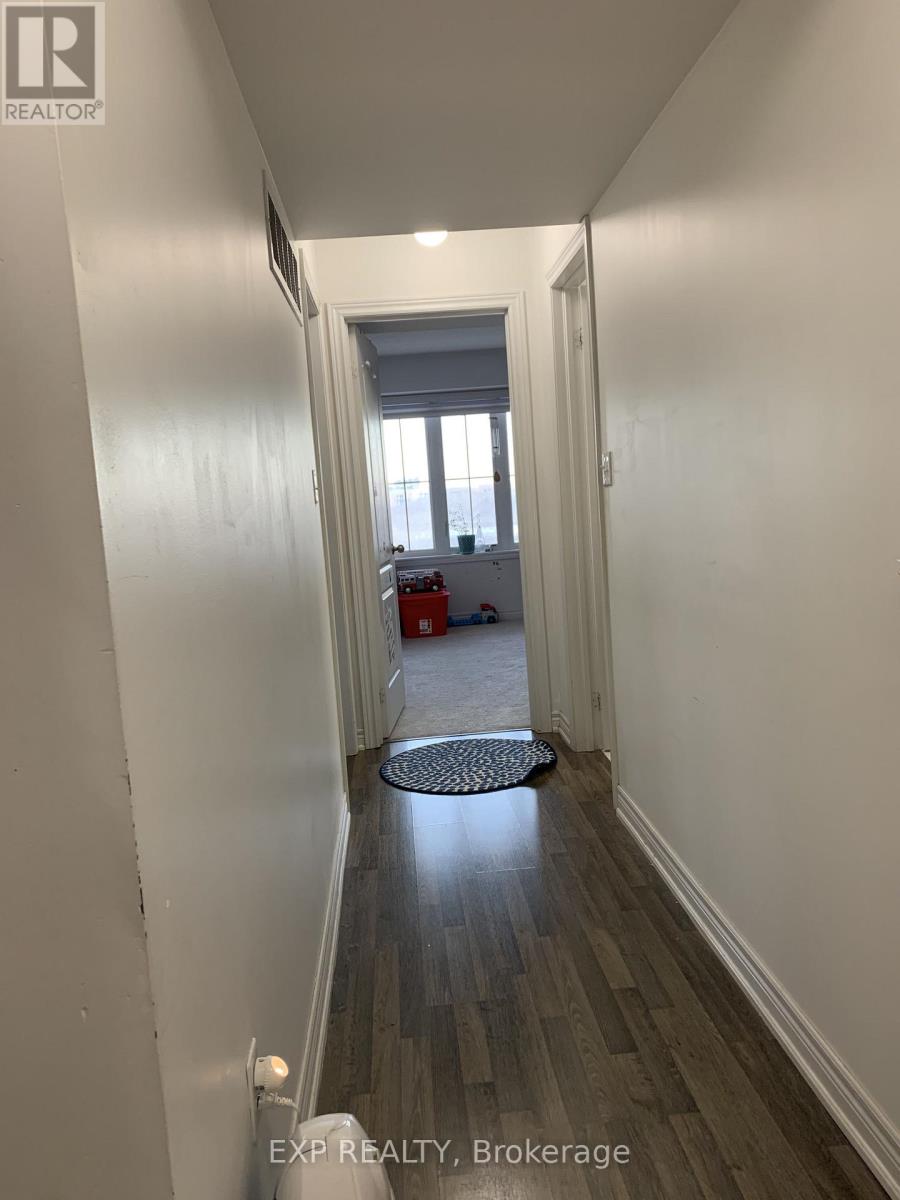 A hallway with a door at the end and a mat on the floor.