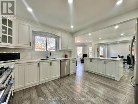 A spacious kitchen with white cabinets and a wooden floor.