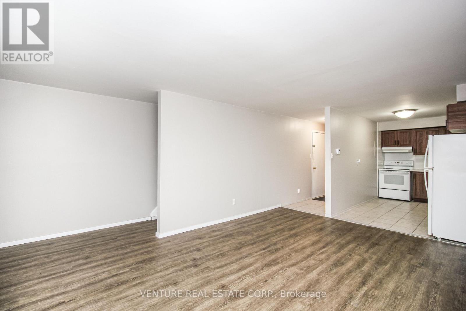 A large, empty room with wood flooring and white walls.