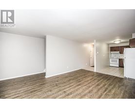 A large, empty room with wood flooring and white walls.