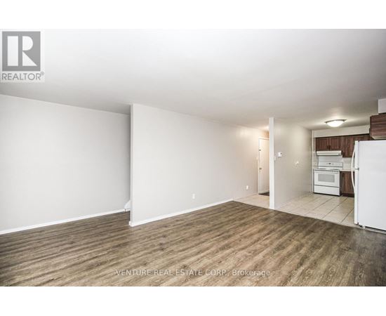 A large, empty room with wood flooring and white walls.