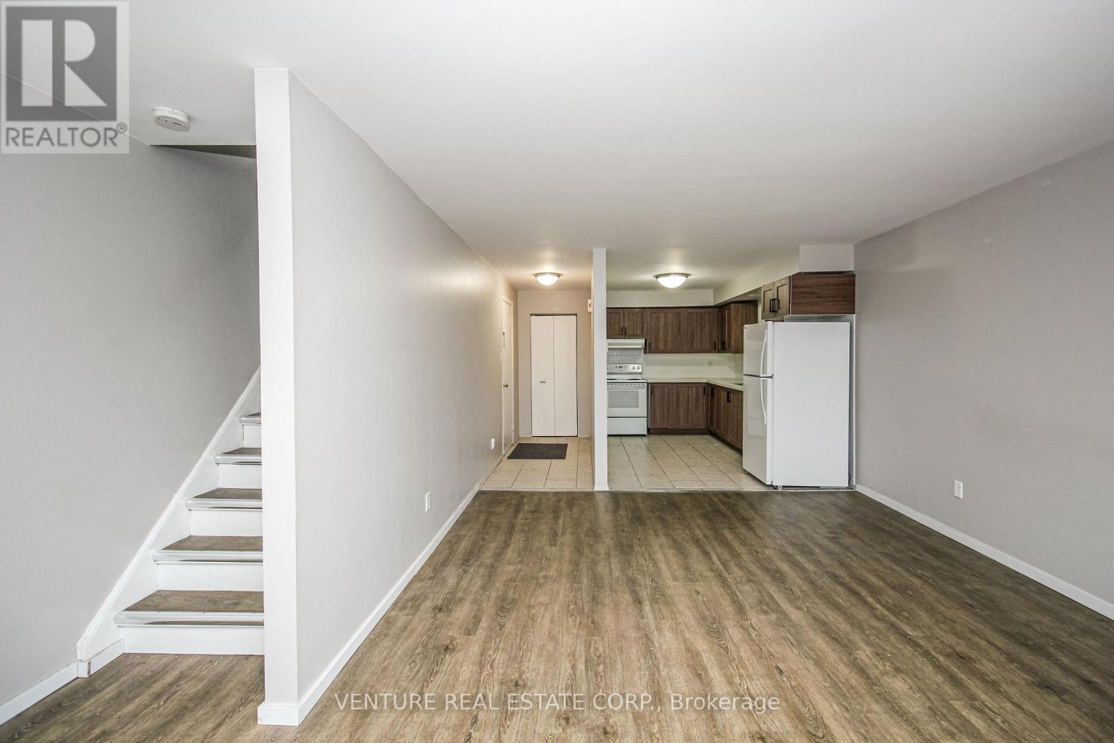 A spacious room with wooden flooring and white walls.