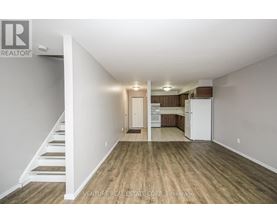 A spacious room with wooden flooring and white walls.