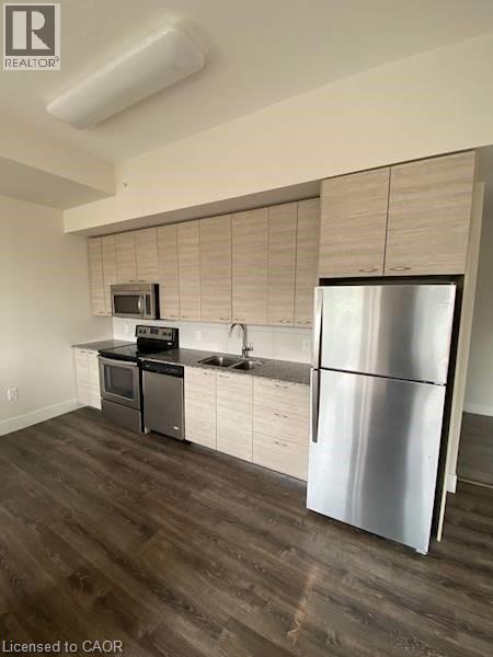 A modern kitchen with a stainless steel refrigerator and wooden flooring.