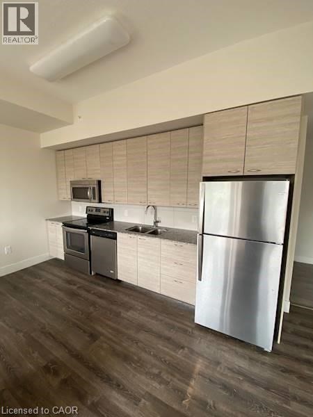 A modern kitchen with a stainless steel refrigerator and wooden flooring.