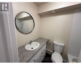 A bathroom with a toilet, sink and mirror.