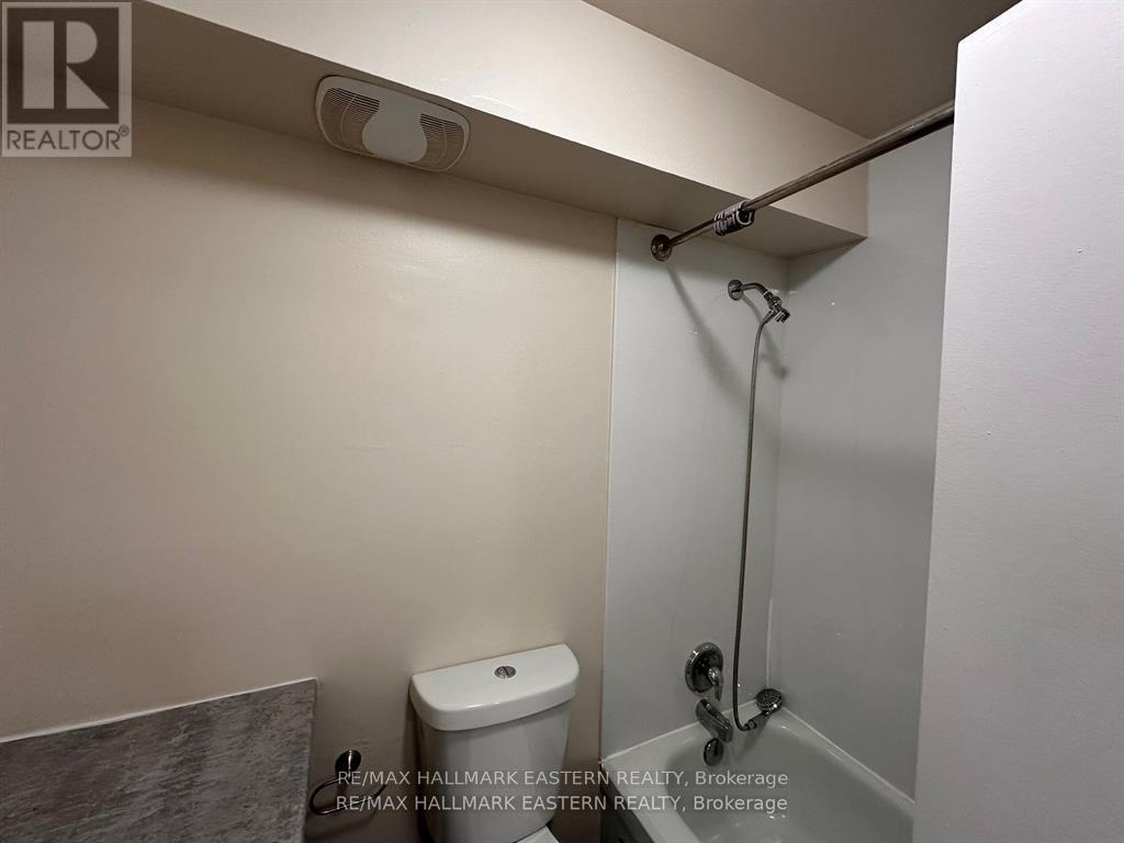 A white toilet in a small bathroom with a shower head above it.