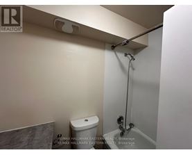 A white toilet in a small bathroom with a shower head above it.