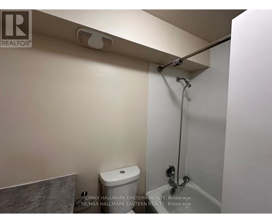 A white toilet in a small bathroom with a shower head above it.