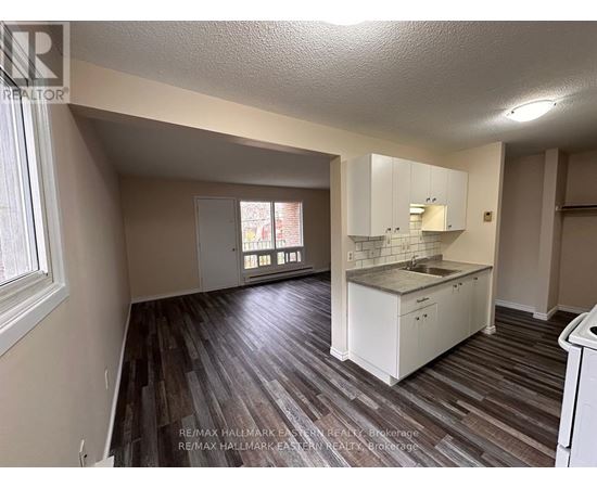 A kitchen area with white cabinets and a wooden floor.
